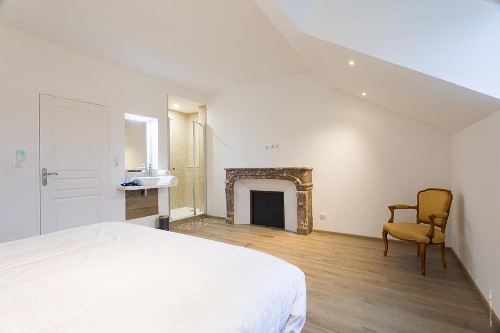 una camera da letto con un letto bianco e un camino di Le Jardin d'Hiver a Chalons en Champagne