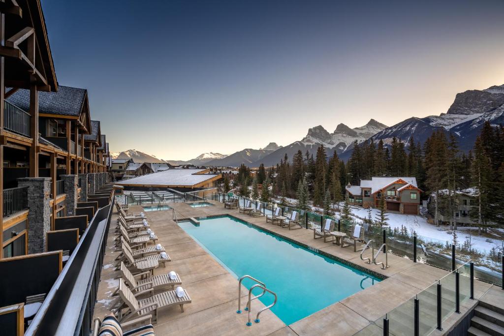 a resort swimming pool with mountains in the background at The Malcolm Hotel in Canmore