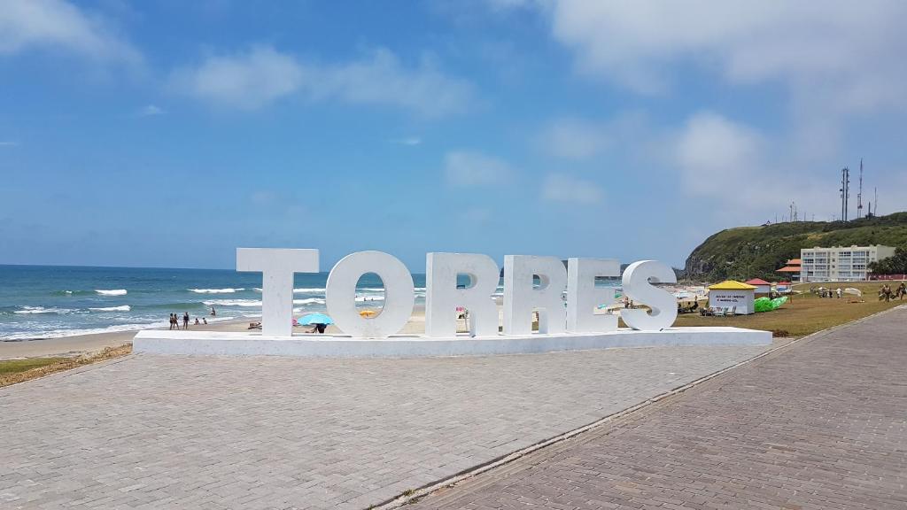un gran cartel en la playa con el océano en el fondo en Apto 2 quartos em Torres-RS, en Torres