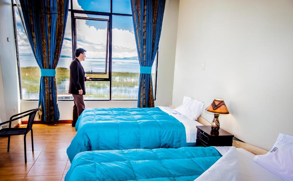 a man standing in a room with two beds and a window at Yacht Lago Titicaca in Ichu