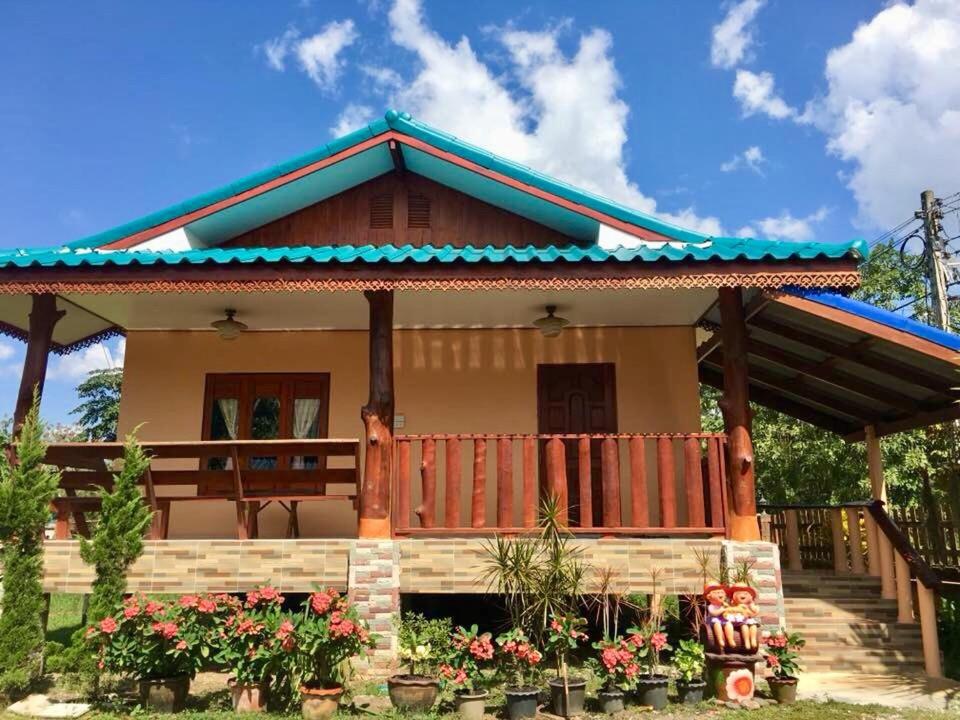 une maison avec une terrasse couverte et des fleurs devant elle dans l'établissement บ้านเรือนทอง, à Chiang Khan