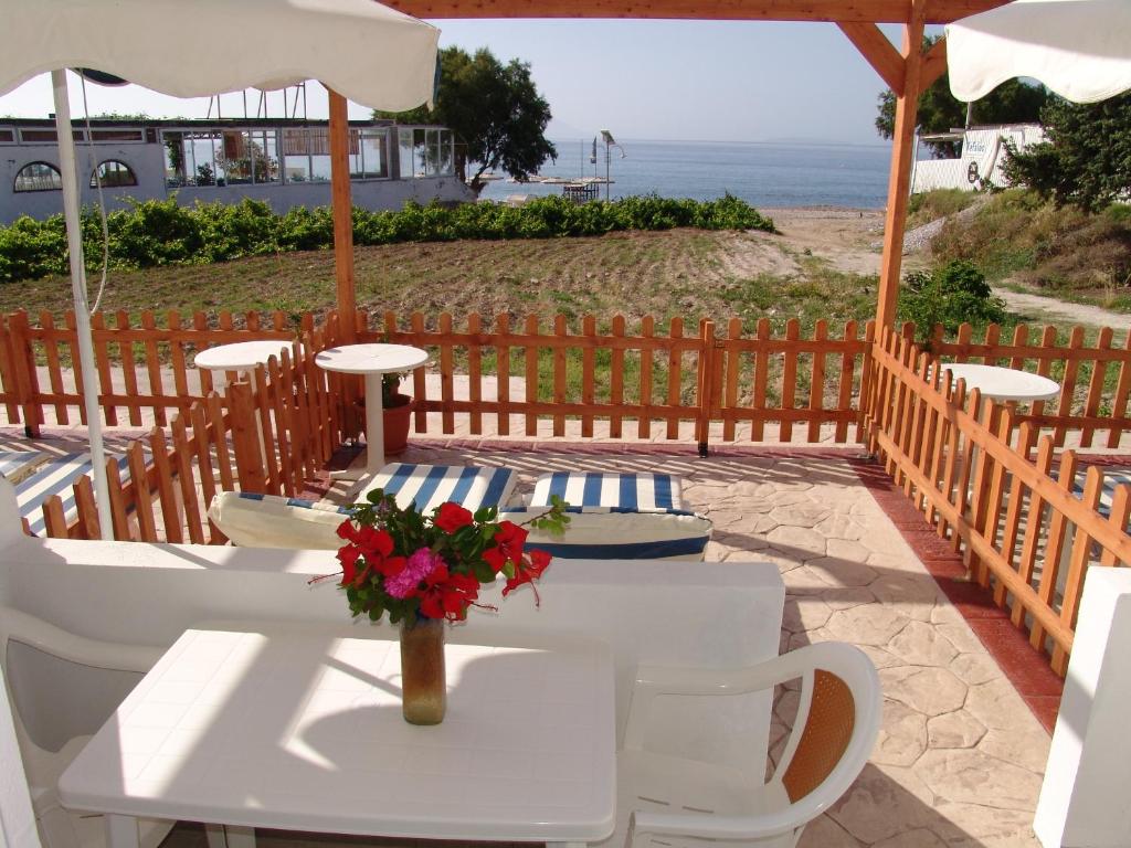 a white table with flowers on a patio with the beach at Irene Studios in Kefalos