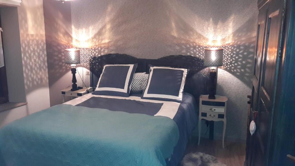 a bedroom with a bed with two pillows and two lamps at Au fil de l'écriture - Appartement sur la Route des Vins à riquewihr in Riquewihr