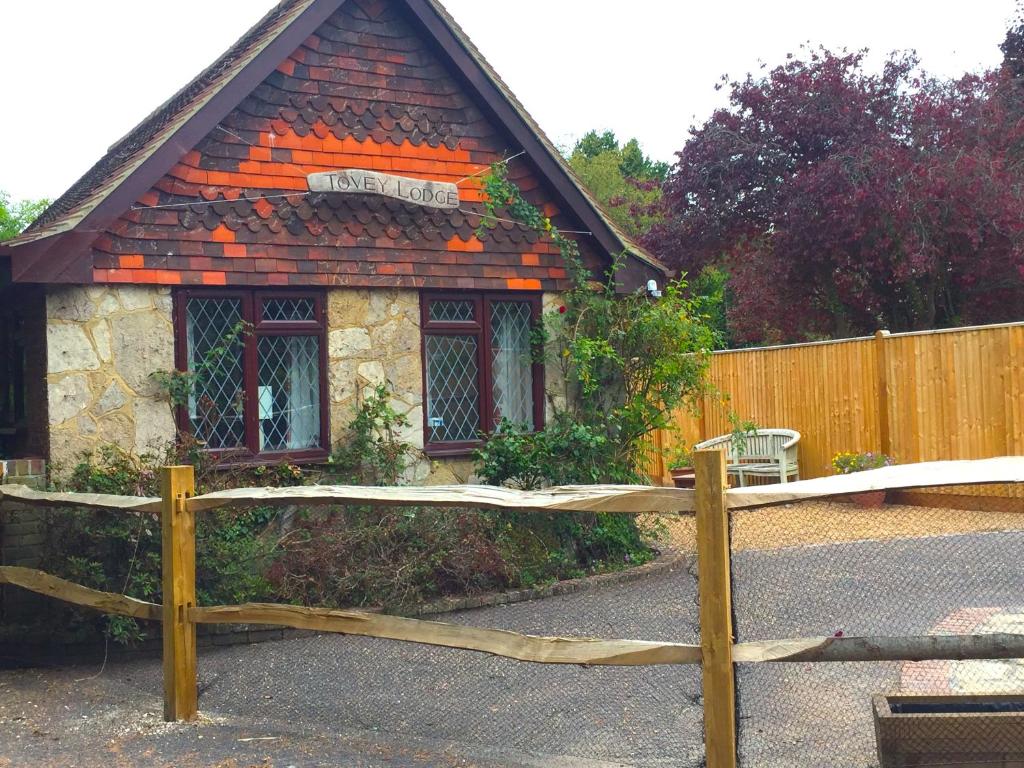 une maison avec une clôture en bois devant elle dans l'établissement Tovey Lodge, à Hassocks
