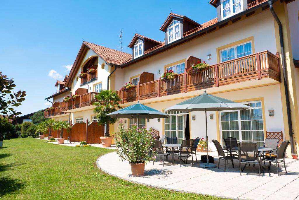 a house with a patio with tables and umbrellas at Glasl's Landhotel in Zorneding