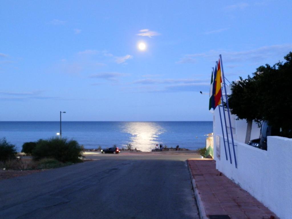 una calle vacía con luna llena sobre el océano en Hotel Mojácar Playa en Mojácar