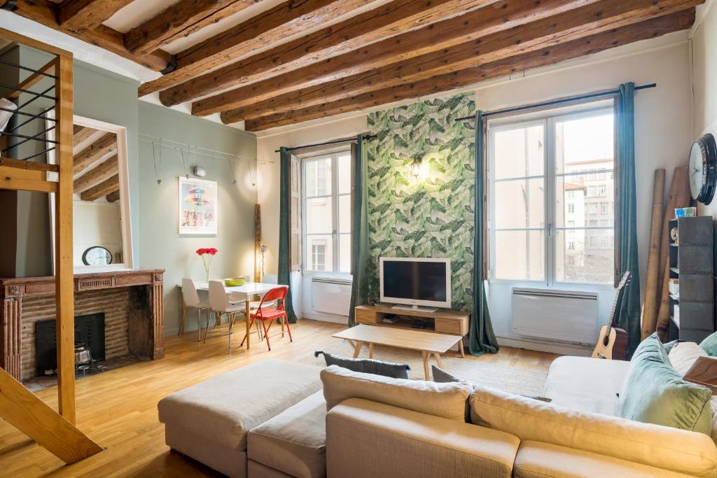 a living room with a couch and a tv at Honorê - Suites Amboise in Lyon