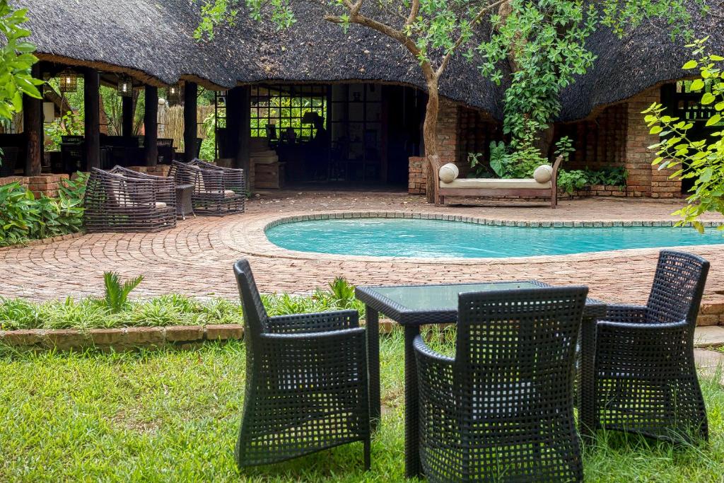 einen Tisch und Stühle neben einem Pool in der Unterkunft The Royal Sichango Village in Livingstone