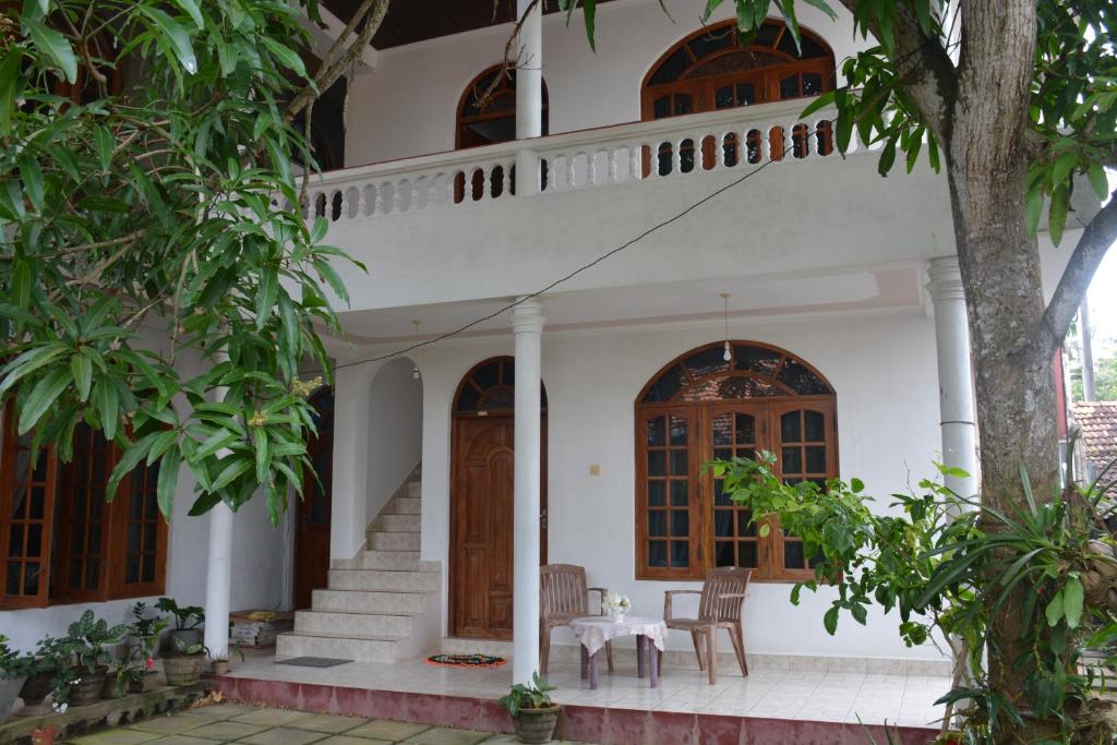 une maison blanche avec une table et des chaises dans l'établissement Welcome Family Guest House., à Bentota