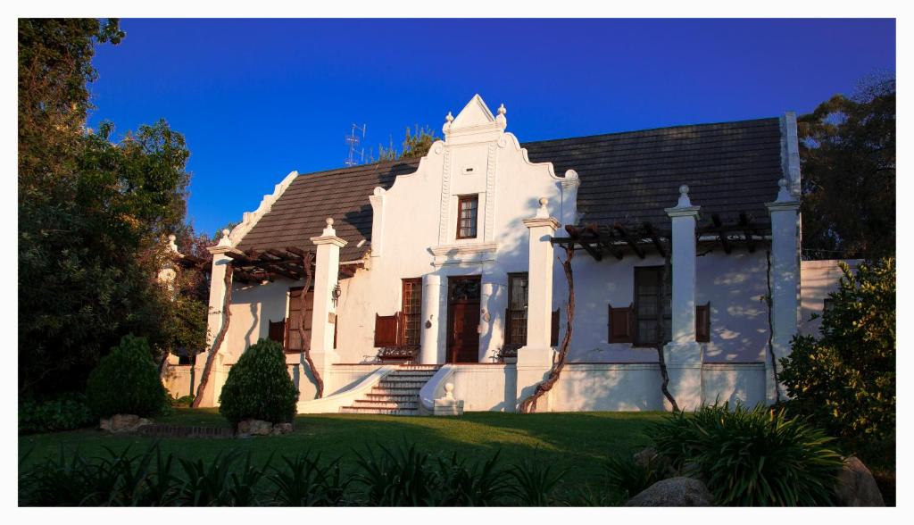 ein weißes Haus mit blauem Himmel im Hintergrund in der Unterkunft Mooiplaas Wine Estate in Stellenbosch