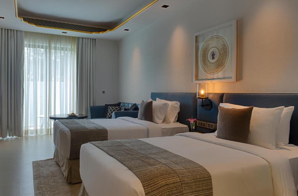 a hotel room with two beds and a couch at Azaya Beach Resort Goa in Benaulim