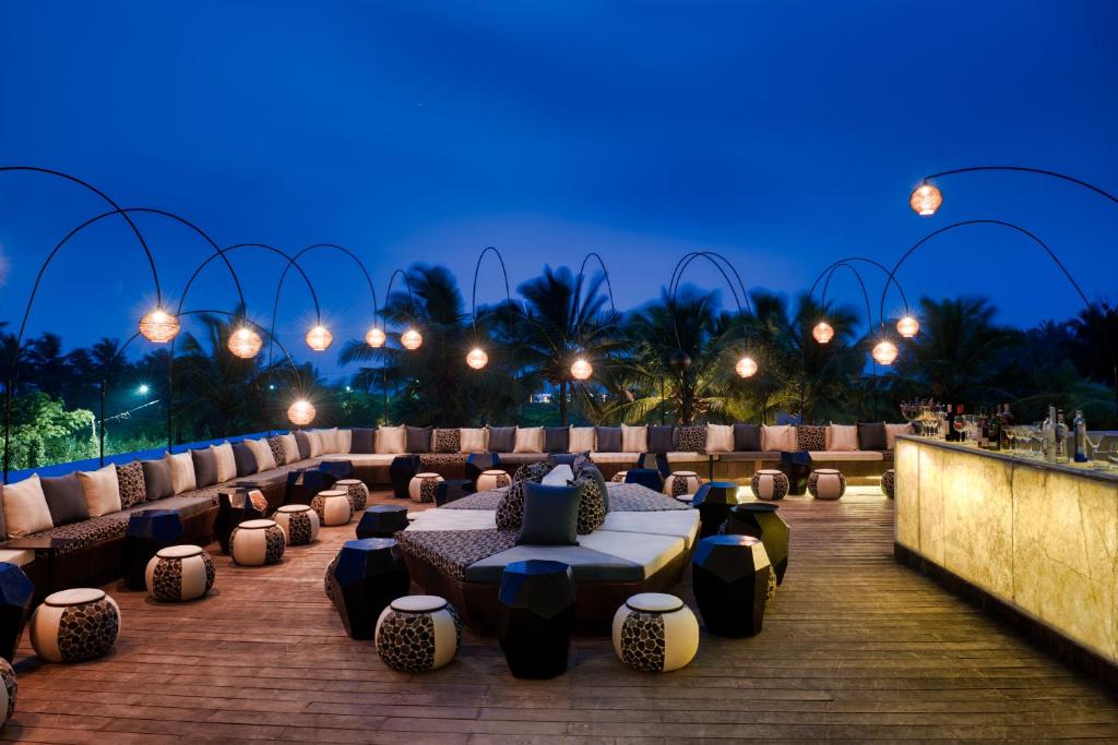 a patio with couches and tables at night at Azaya Beach Resort Goa in Benaulim