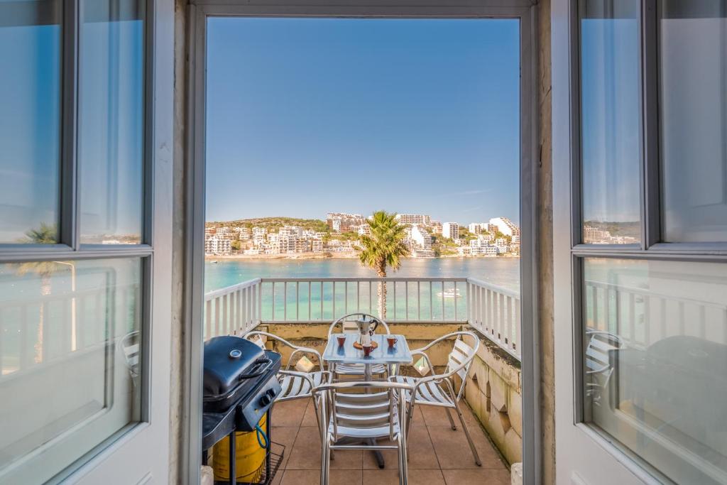a balcony with a table and chairs and a view of the water at Blue Harbour 2 bedroom Seafront Apartments with large terrace with spectacular sea views - by Getawaysmalta in St. Paul's Bay