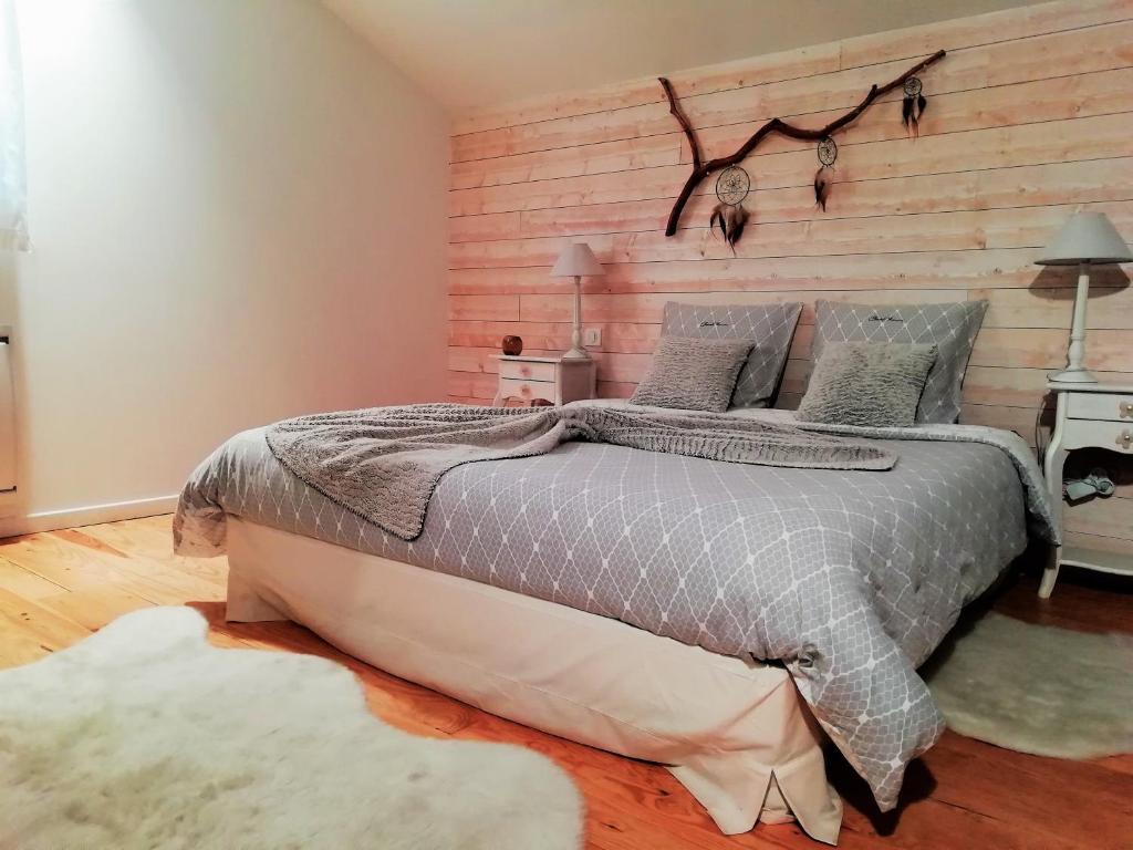 1 dormitorio con 1 cama grande y pared de madera en La Magie des Rêves, en Montréjeau