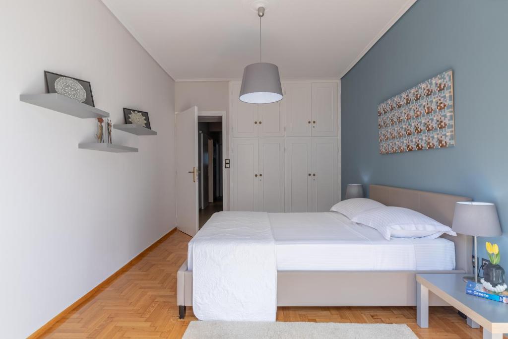 a bedroom with a white bed and a blue wall at Tranquil Central Apt, behind Athens Caravel Area in Athens