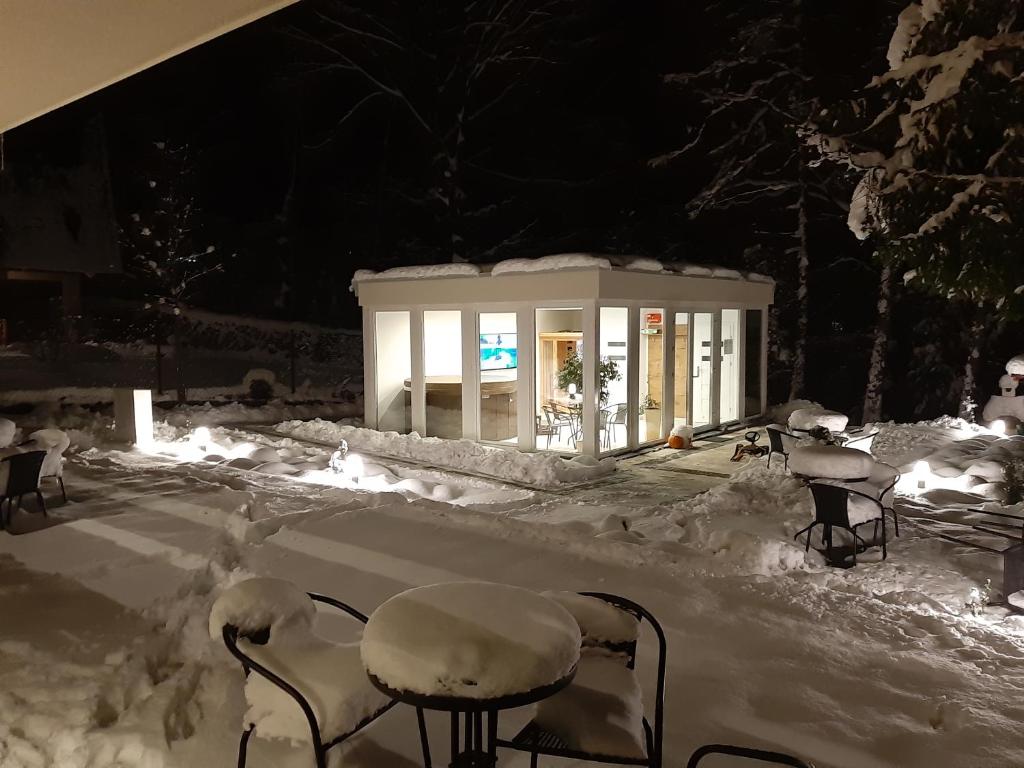 eine schneebedeckte Terrasse mit Stühlen und Tischen in der Nacht in der Unterkunft Apartamenty Skalite Szczyrk Wellness in Szczyrk