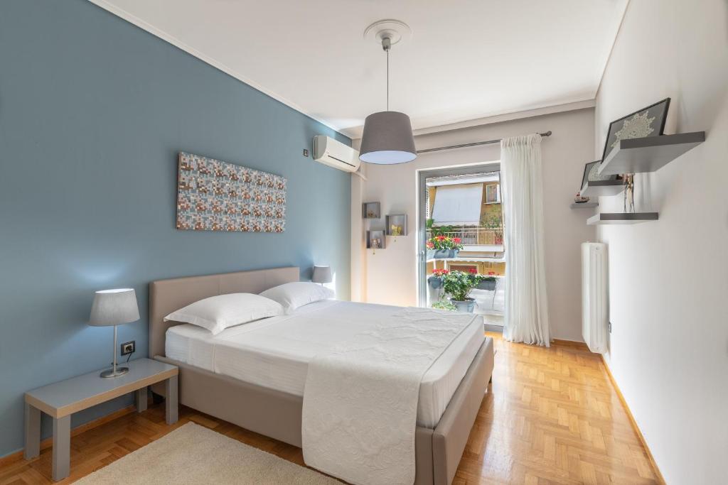 1 dormitorio con cama blanca y pared azul en Tranquil Central Apt, behind Athens Caravel Area, en Atenas
