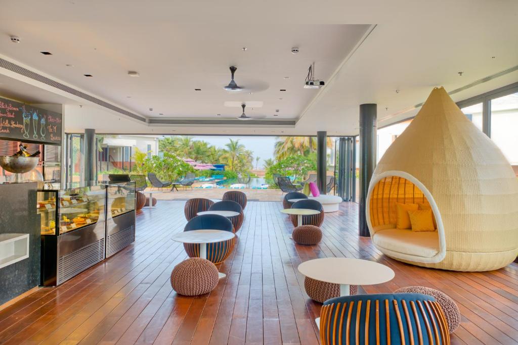 a lobby with tables and a couch and chairs at Azaya Beach Resort Goa in Benaulim