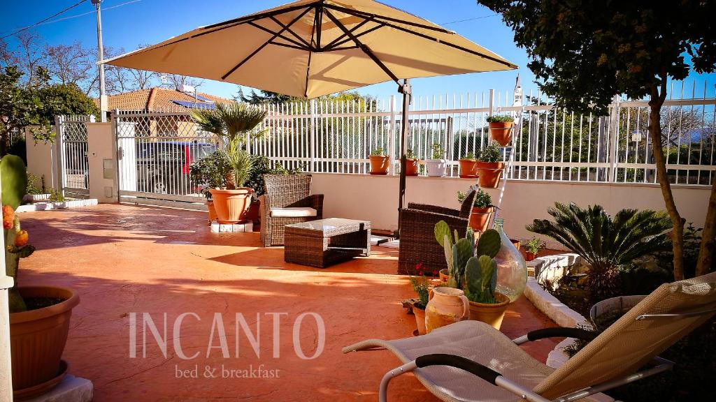 a patio with an umbrella and chairs and plants at Incanto b&b in Lesina