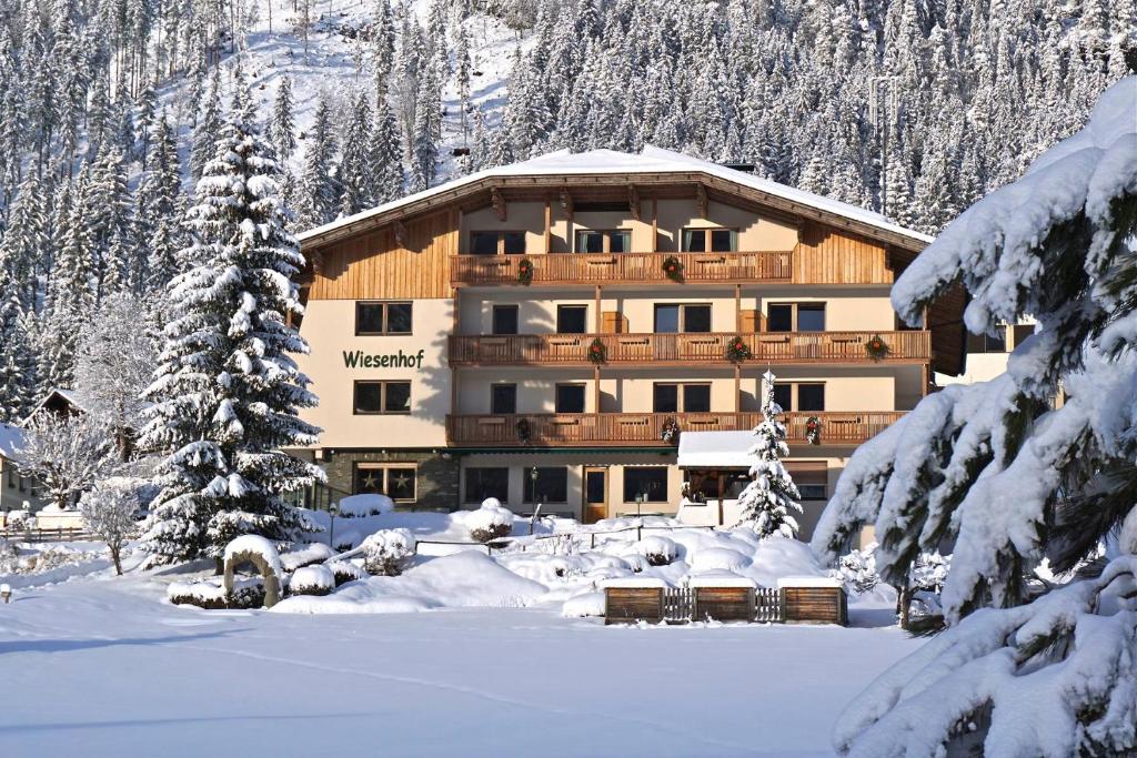a large building in the snow with snow covered trees at Wiesenhof, Hotel direkt am See in Weissensee