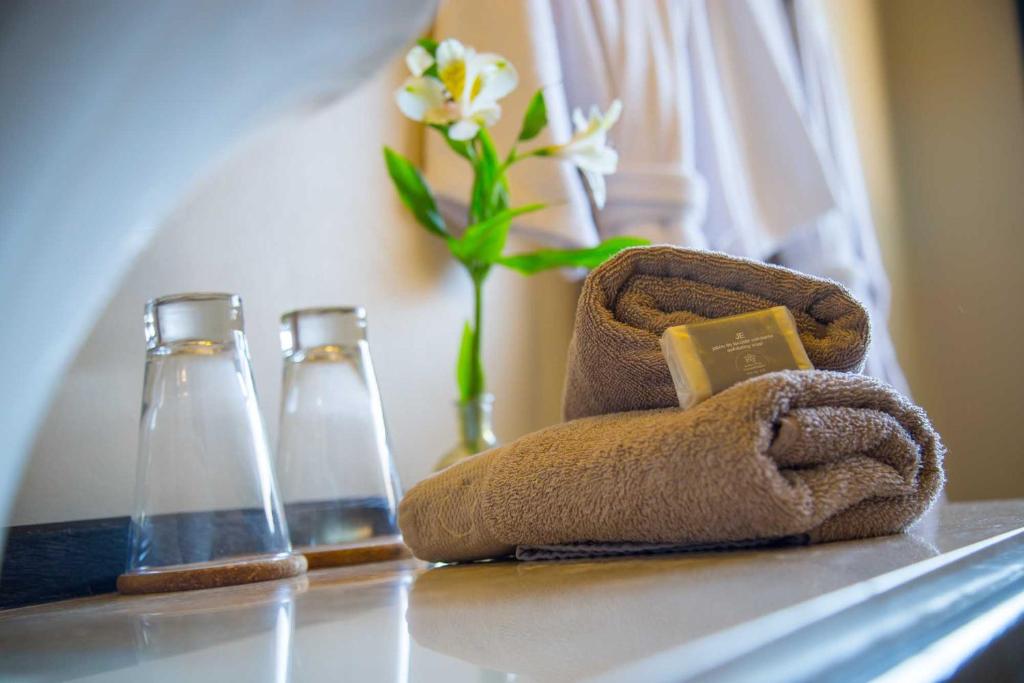 two bottles and a towel with a flower in a vase at Ayres del Champaqui Hotel Boutique Experiencial & Spa in Villa General Belgrano