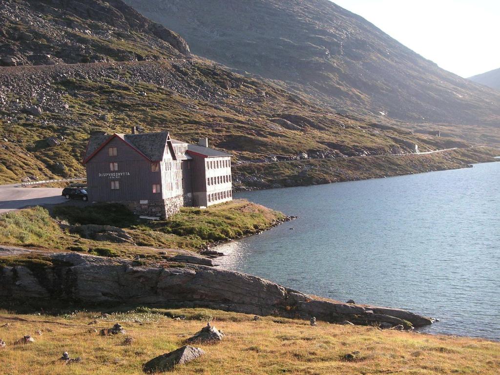 a building on a hill next to a body of water at Djupvasshytta Bed & Breakfast in Geiranger