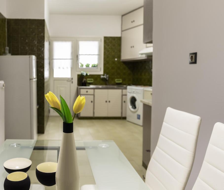 a kitchen with a table with yellow flowers in a vase at Tranquil Central Apt, behind Athens Caravel Area in Athens