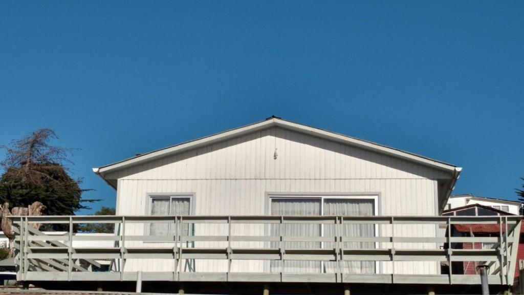 a white building with a fence in front of it at Bonita casa con vista al mar Las Cruces El Tabo in Las Cruces