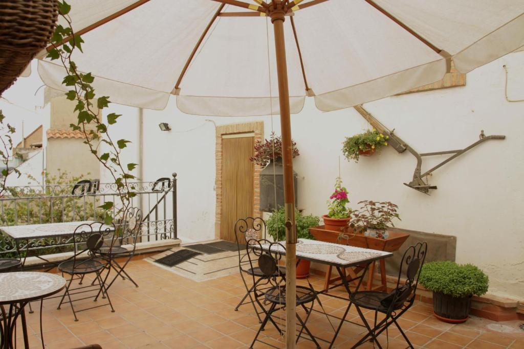 a patio with tables and chairs and an umbrella at Casa Rural "La Bardena Blanca I " in Arguedas