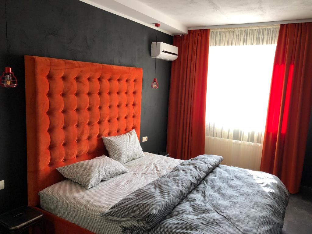 ヴィーンヌィツャにあるЭксклюзивная квартираのベッドルームにオレンジのヘッドボード付きのベッド1台