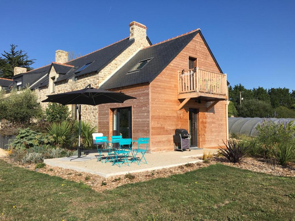 a house with a deck and chairs and an umbrella at Kervran in Plouhinec