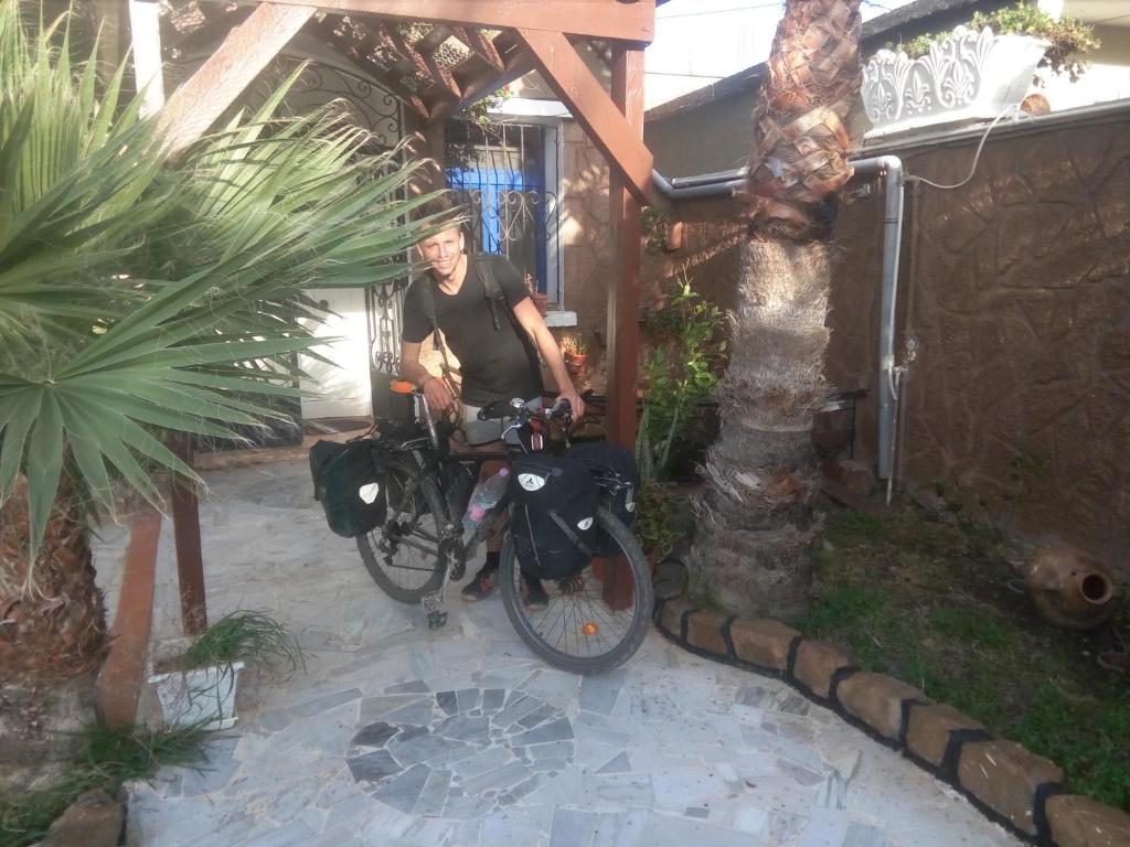 Un uomo seduto su una bicicletta in un cortile di Hotel plage d'or a Jijel