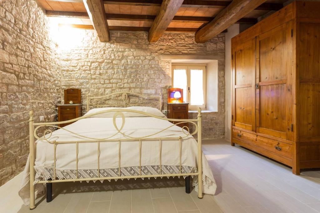 een slaapkamer met een bed en een bakstenen muur bij Villa Costanzi: Beautiful Rural Apartment! in Sigillo