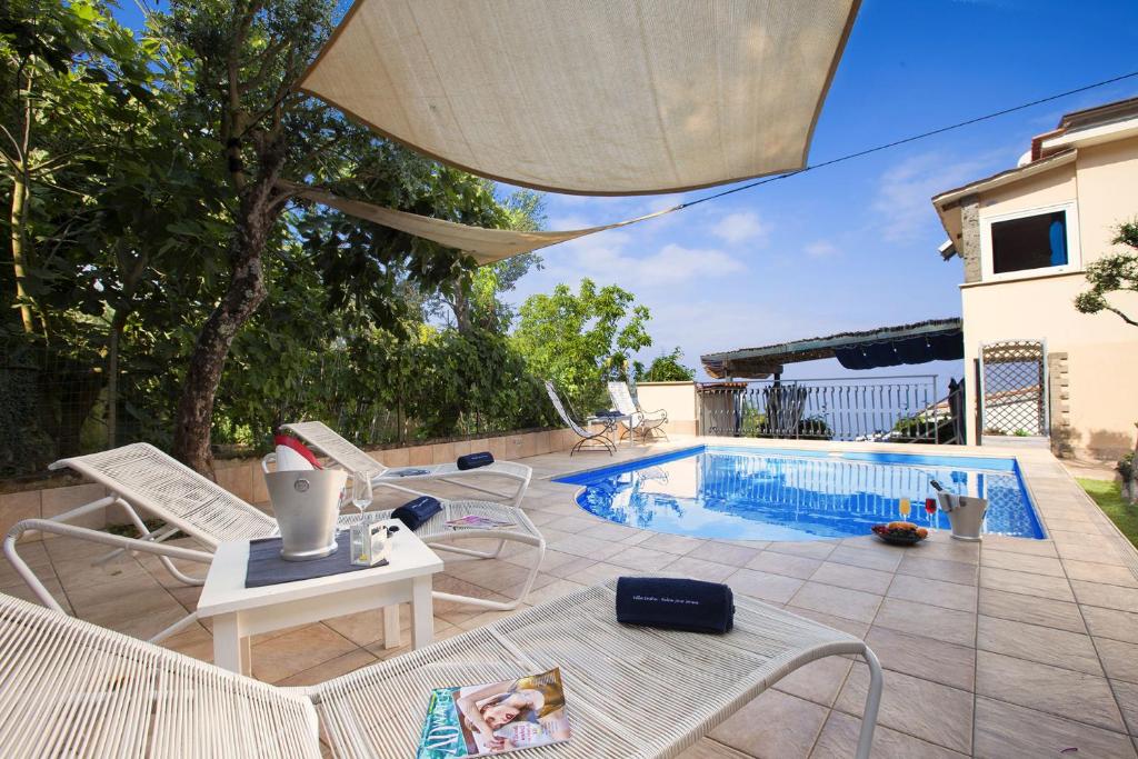 eine Terrasse mit einem Pool, Stühlen und einem Tisch in der Unterkunft AMORE RENTALS - Villa Felice in Massa Lubrense