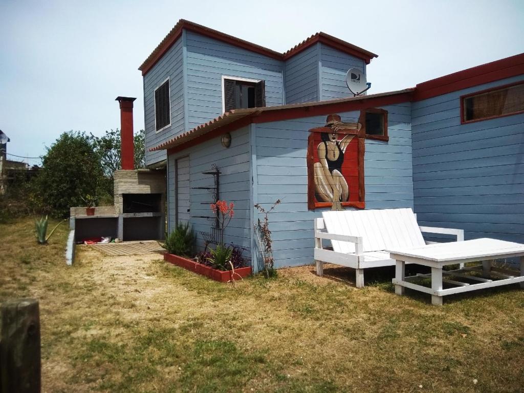 uma casa azul com um banco e um quadro em AMBRA em Punta Del Diablo