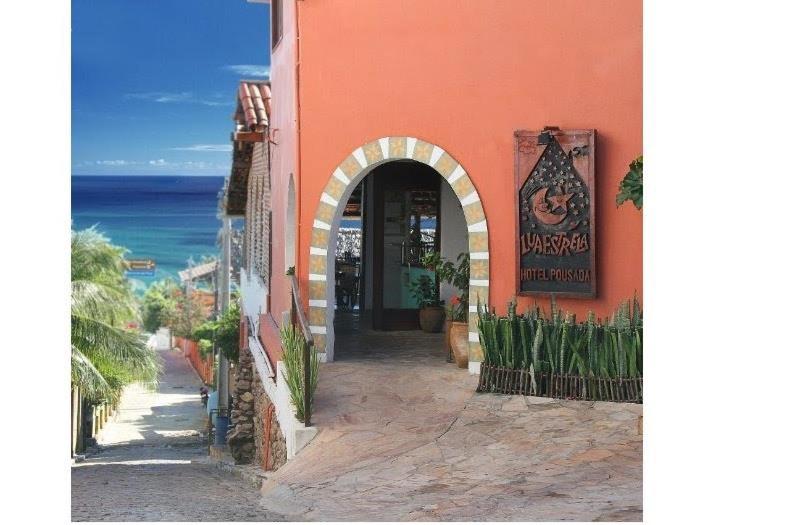 an entrance to a building with the ocean in the background at Pousada Lua Estrela in Canoa Quebrada