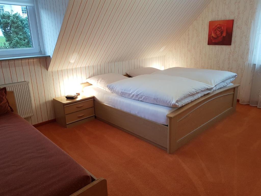 a bedroom with a bed with white sheets and a window at Ferienhaus "Am Gehre" in Bad Berleburg