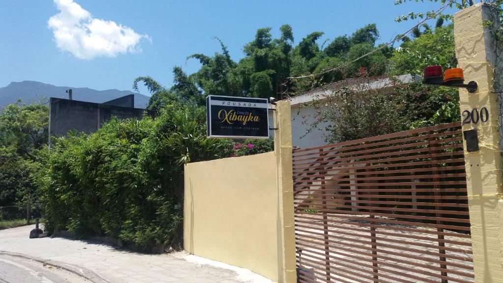 a gate with a sign on the side of a building at Chalés Xibayka Ilhabela in Ilhabela