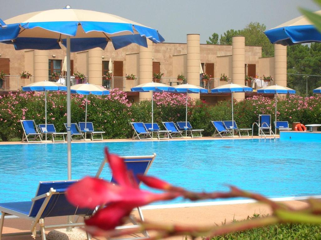 a swimming pool with blue chairs and umbrellas at Cosmopolitan Golf & Beach Resort in Tirrenia