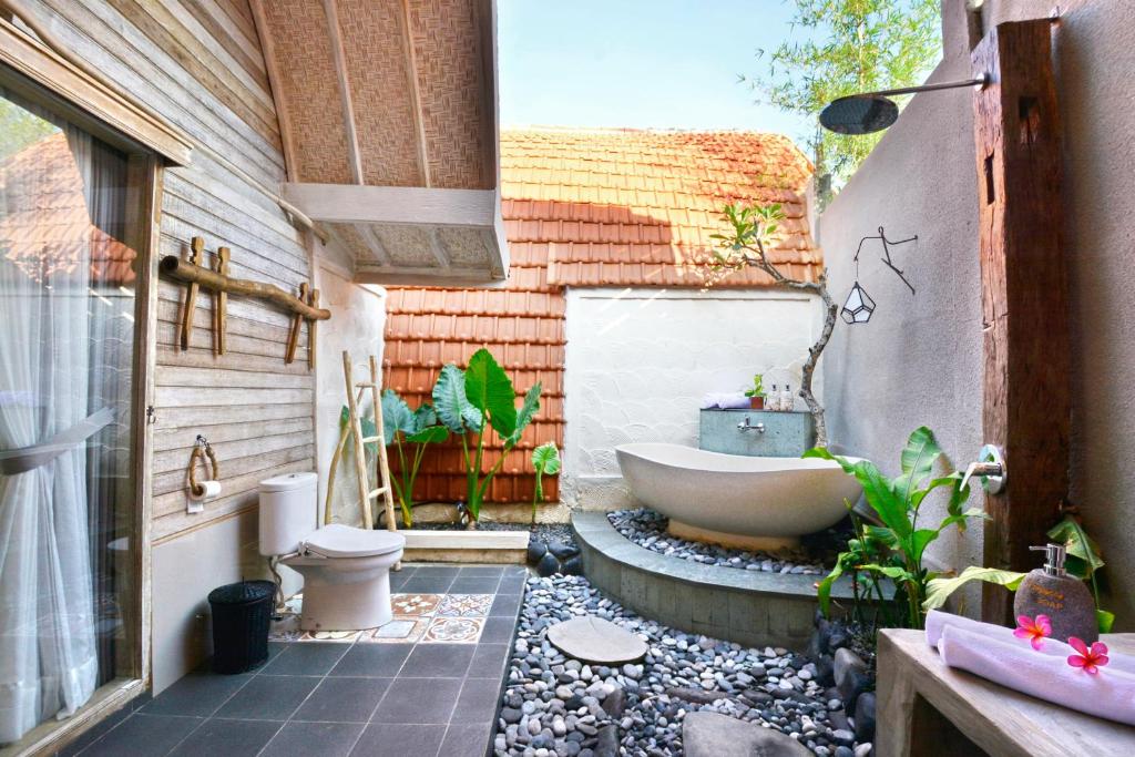 a bathroom with a tub and a toilet and a sink at Kompyang Cottage in Nusa Penida