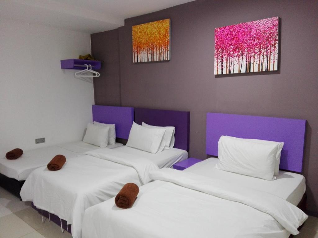 two beds in a room with two paintings on the wall at The Serai Cottage Boutique Hotel in Kuala Berang