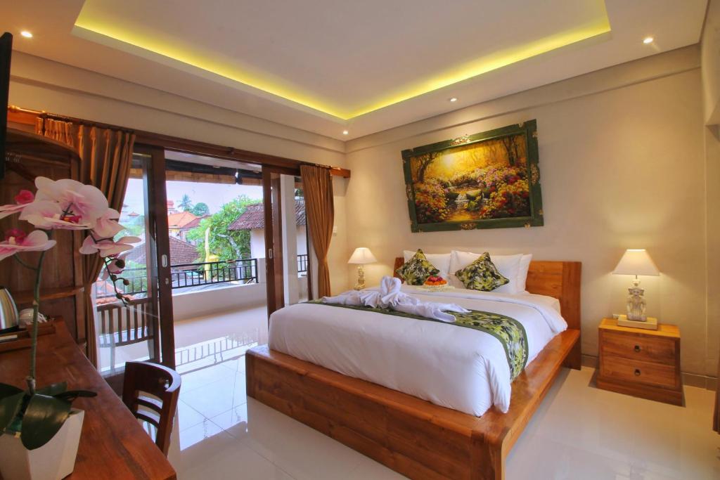 a bedroom with a large bed and a balcony at Meranggi Home Stay in Ubud
