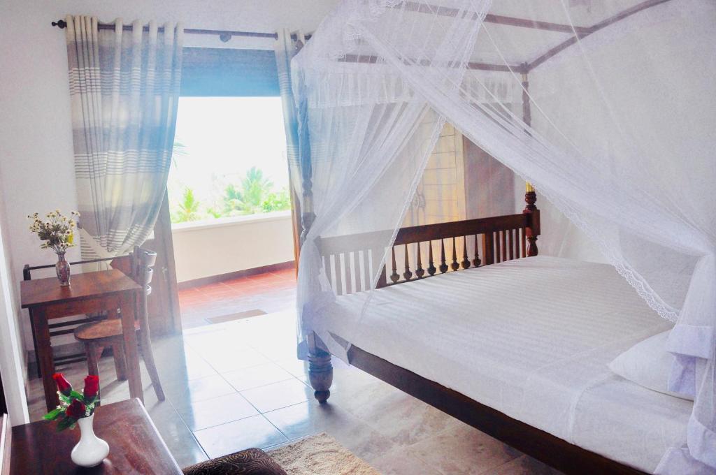 a bedroom with a canopy bed with a desk and a window at Supun Villa in Bentota