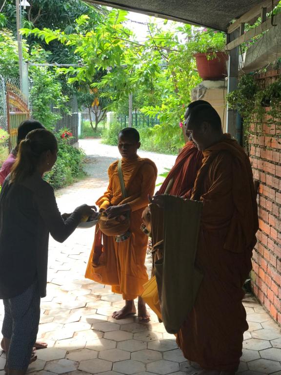 a woman is shaking hands with a monk at Madam Sokha Homesteading in Siem Reap
