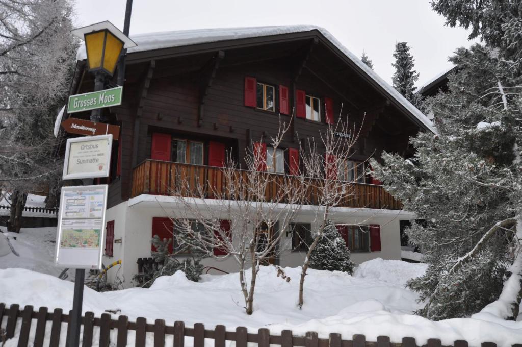 ein Gebäude mit roten Fensterläden im Schnee in der Unterkunft Chalet Minga Mal in Saas-Fee