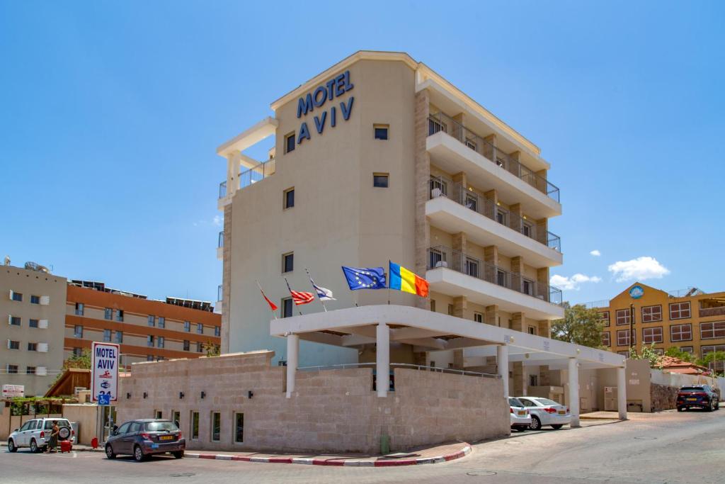 ein Hotelgebäude mit Flaggen davor in der Unterkunft Motel Aviv in Eilat