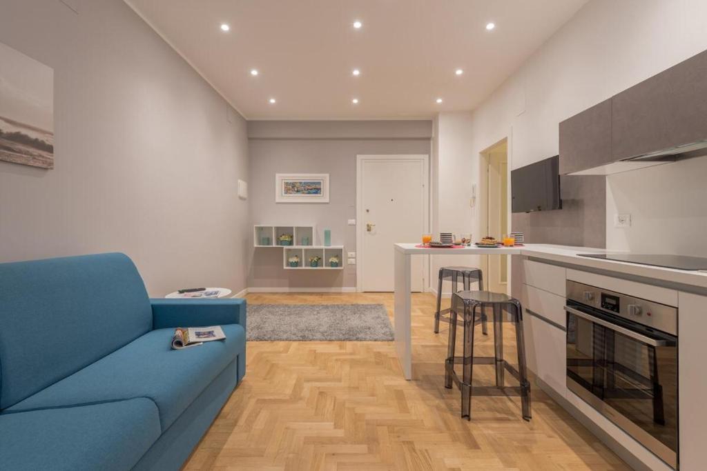 Linda House في بيسكارا: غرفة معيشة مع أريكة زرقاء ومطبخ