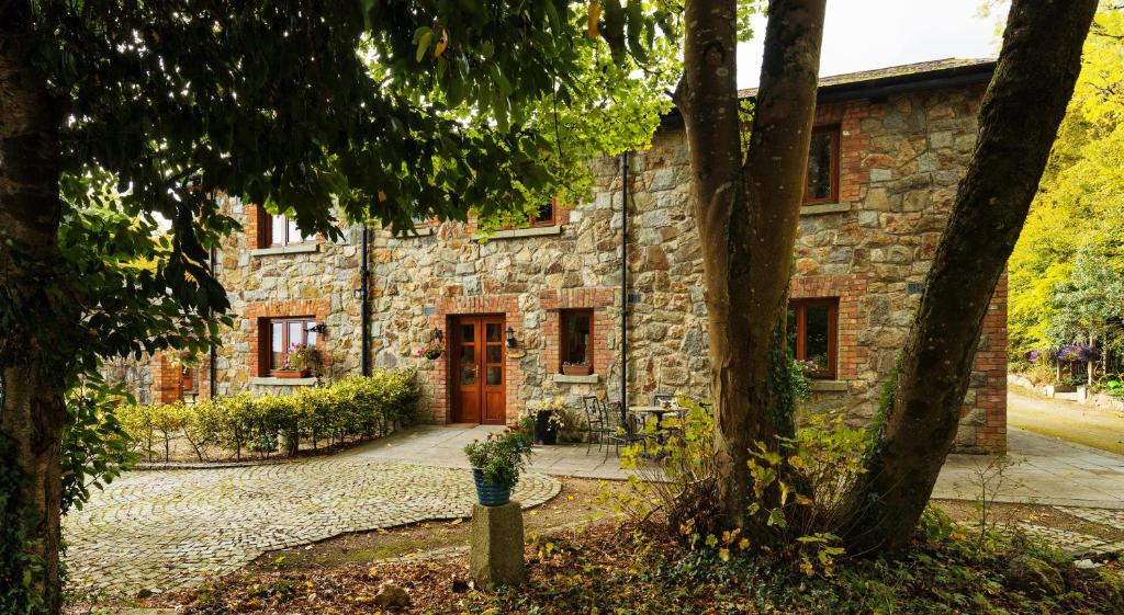 a stone house with a red door and trees at Croneybyrne Courtyard in Clara