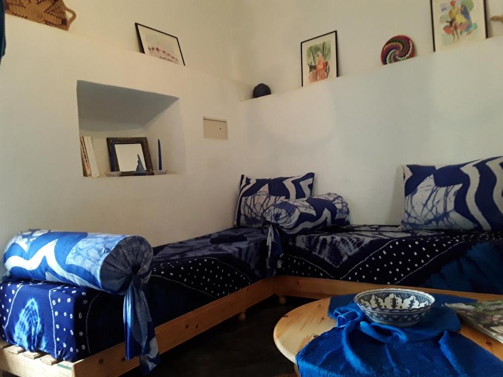 een woonkamer met 2 bedden en een tafel bij La Maison Bleue in Sidi Ifni