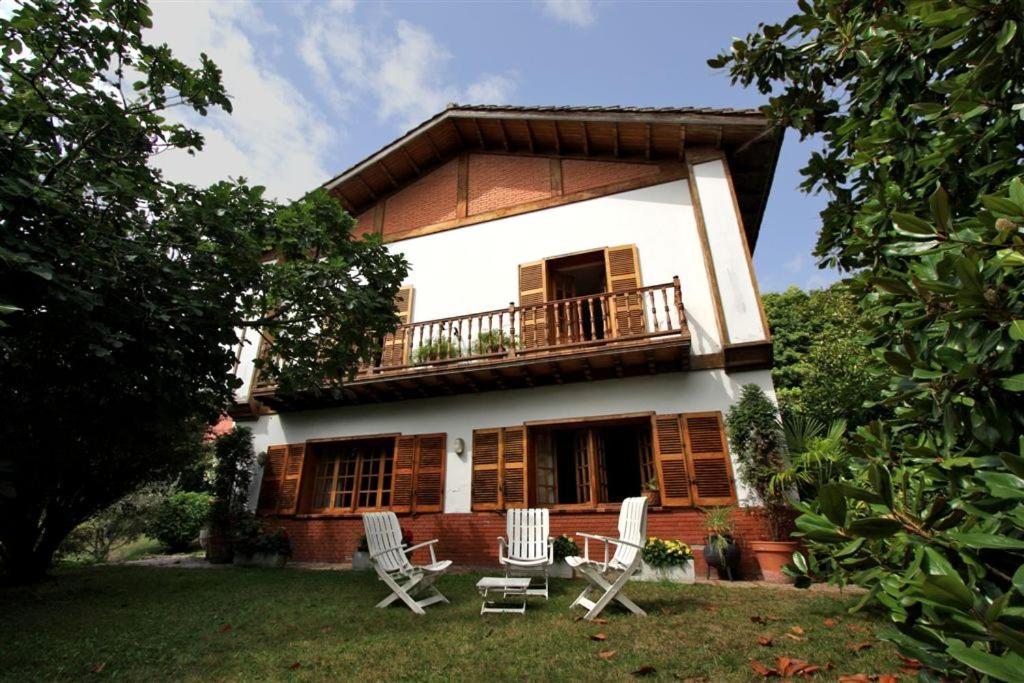 ein Haus mit einem Balkon und Stühlen im Hof in der Unterkunft El Berdial in San Esteban de Pravia